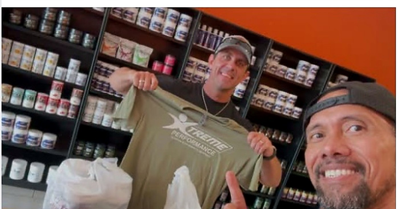 Customer holding up an Xtreme Performance Nutrition t-shirt in the Gonzales store